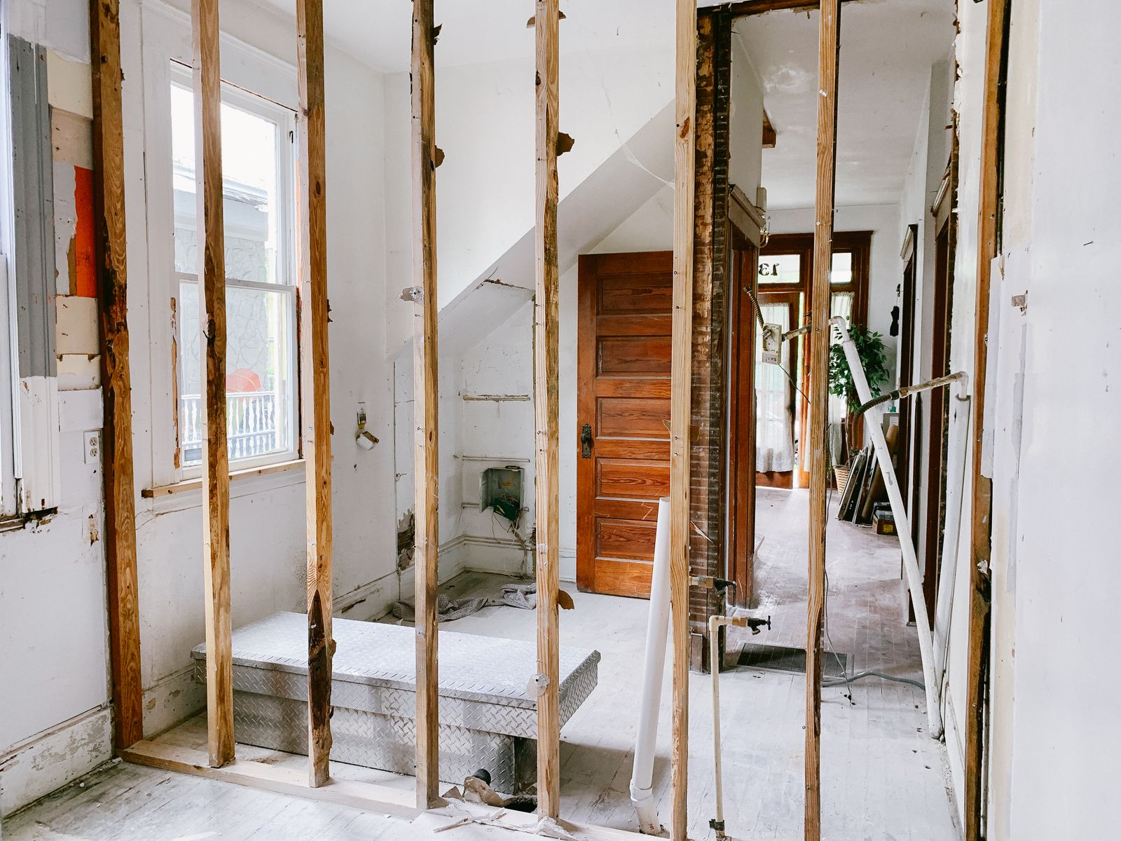A room gutted to exposed timber studs with original doors leaning nearby