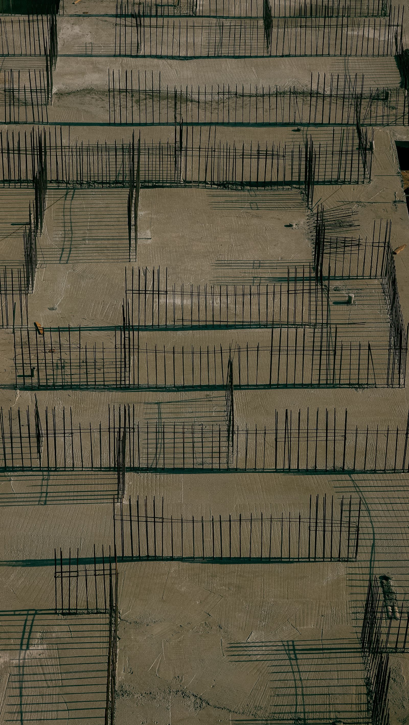 An aerial view of concrete foundations and rebar grids on a construction site