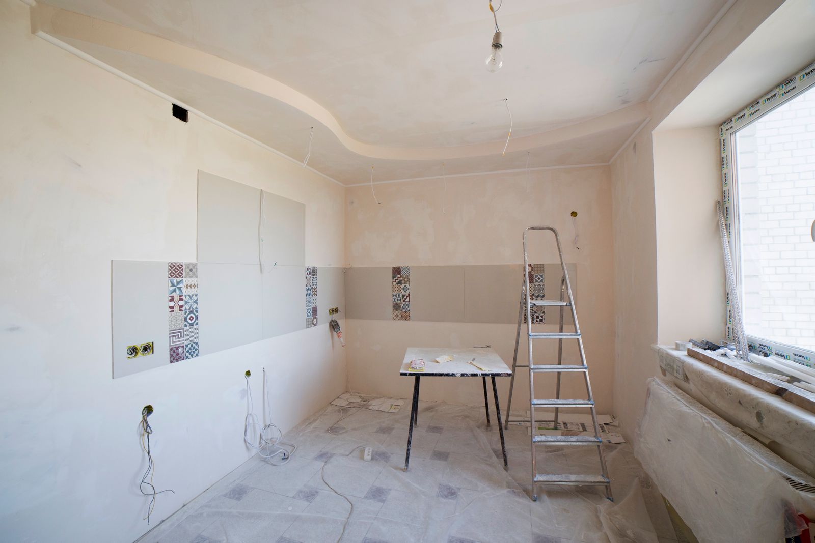 A room mid-renovation with a step ladder and tile samples on the wall